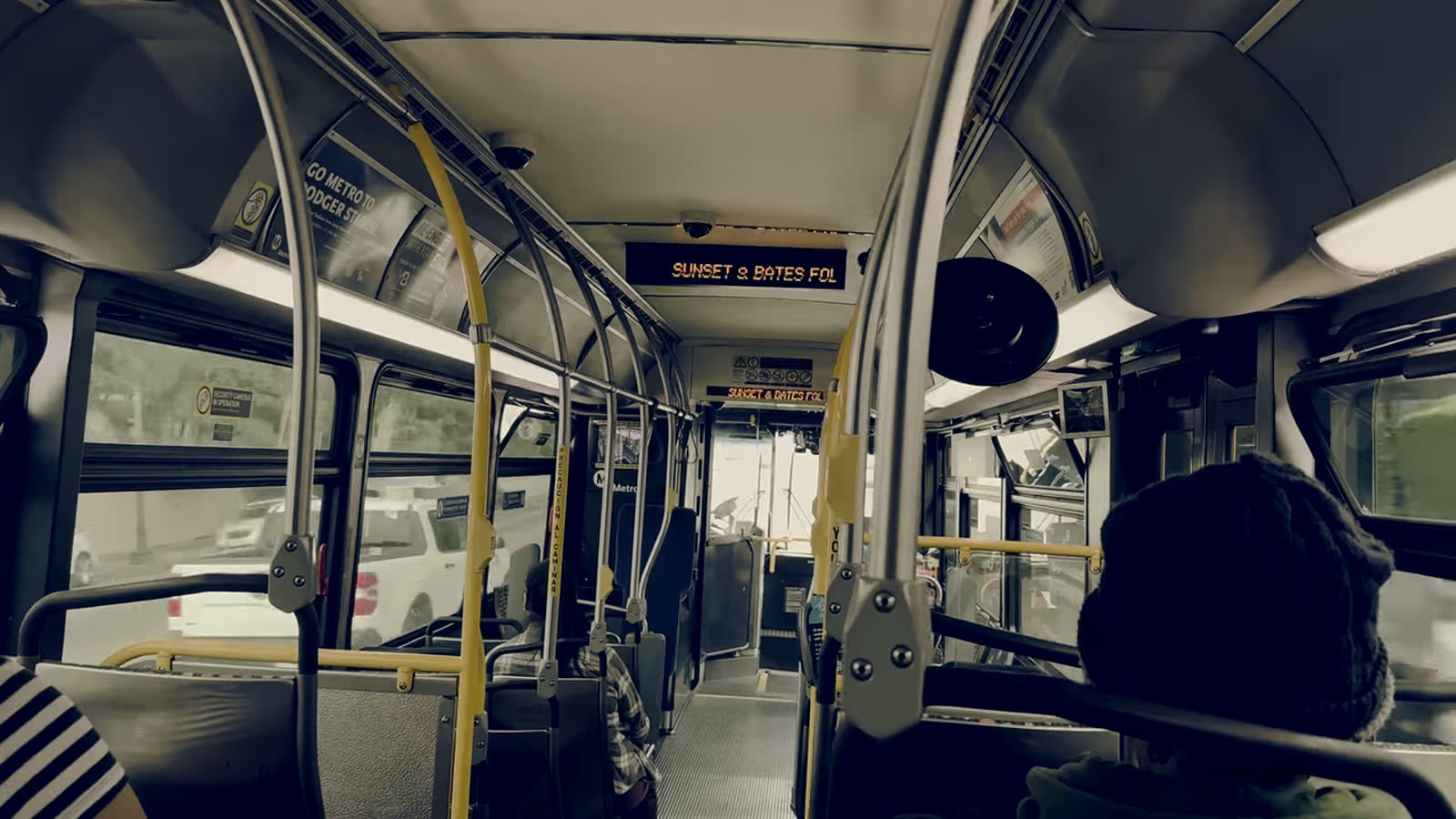 Interior real de un autob&uacute;s urbano en ruta, con letrero LED a bordo y pasajeros de espaldas