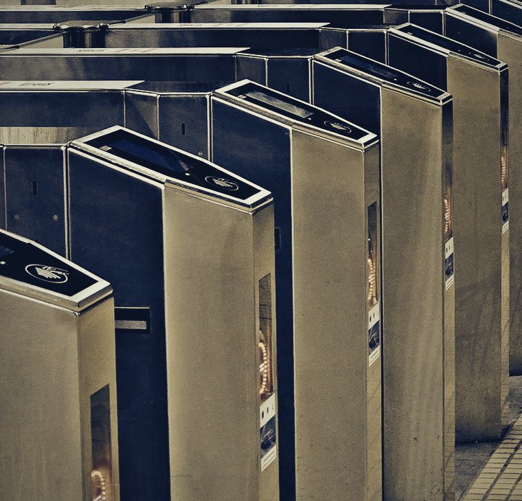 Fila de torniquetes de peaje de una estaci&oacute;n, con lectora sin contacto y barra de LED en rojo