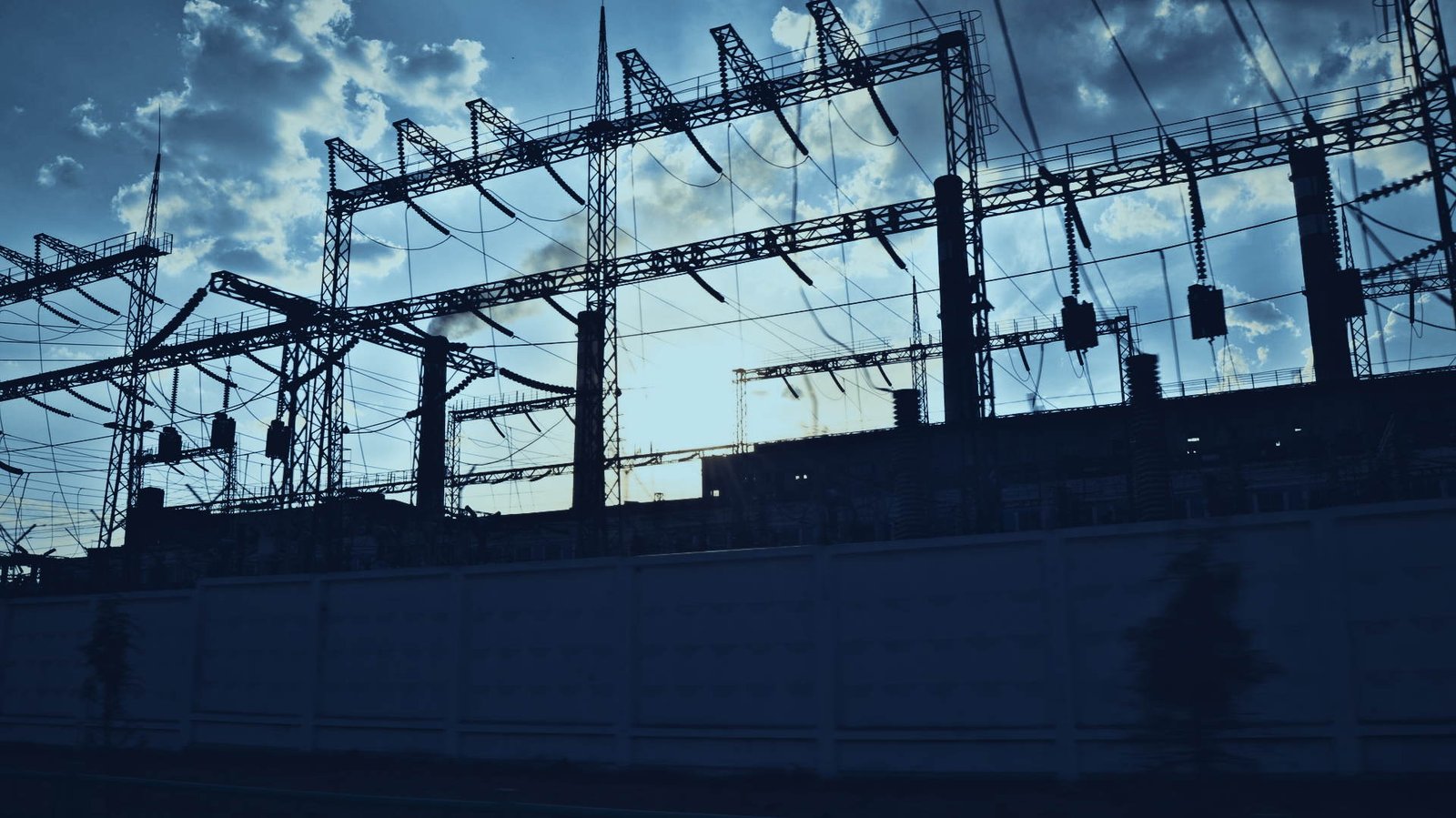 Subestaci&oacute;n el&eacute;ctrica a contraluz, transformadores y estructura de cuchillas al final de la tarde