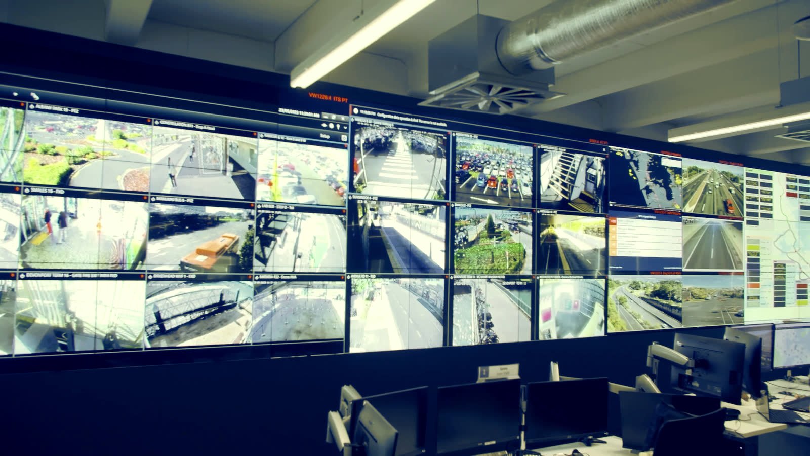 Muro de c&aacute;maras de un centro de monitoreo con operadores de espaldas en turno